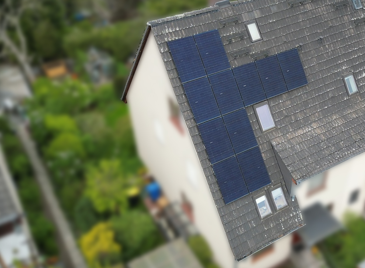 Aus der Luft aufgenommen: Spitzdach eines Mehrfamilienhauses mit Solarmodulen einer Photovoltaikanlage